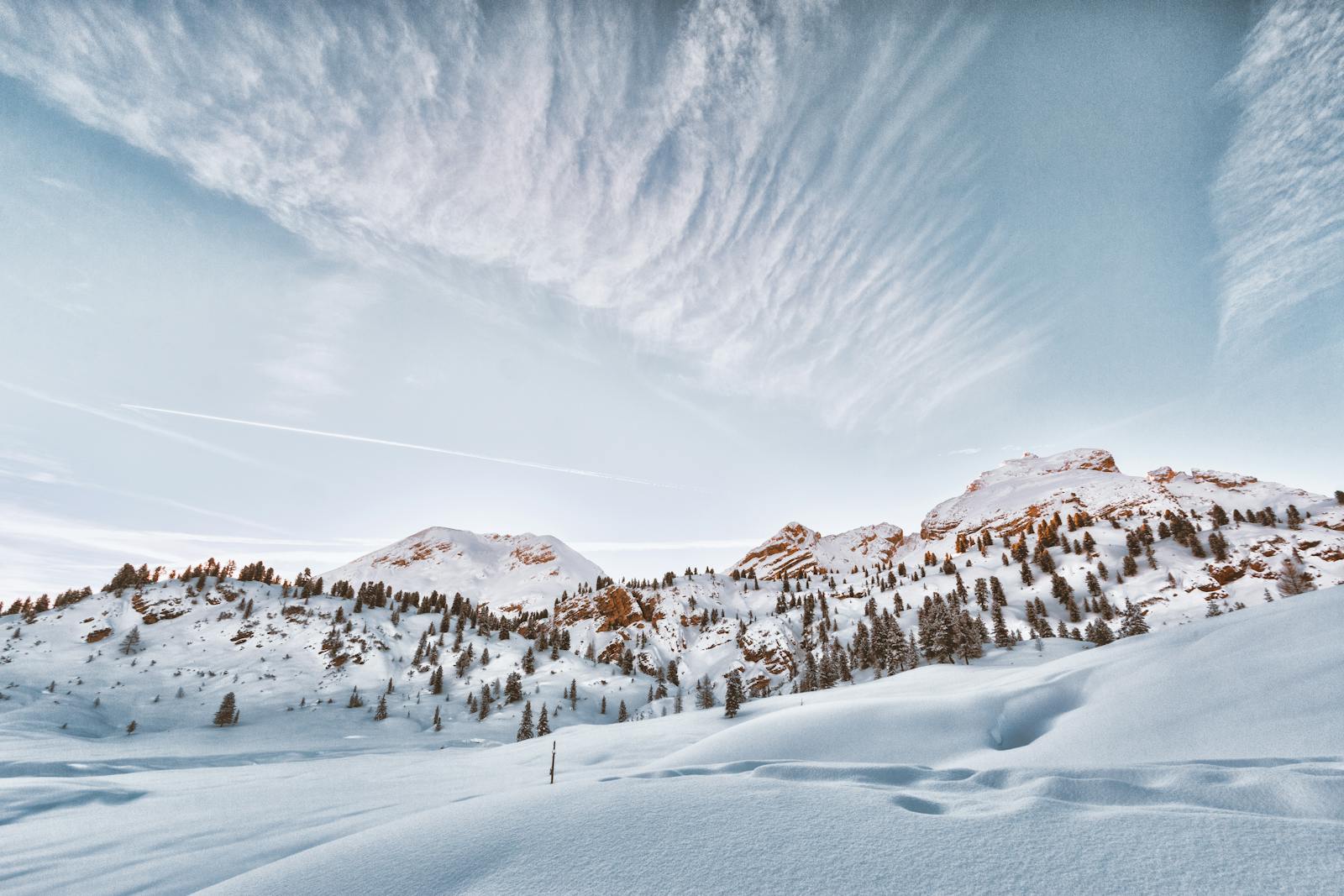 Breathtaking snowy mountain landscape with trees and clouds in the Dolomites.