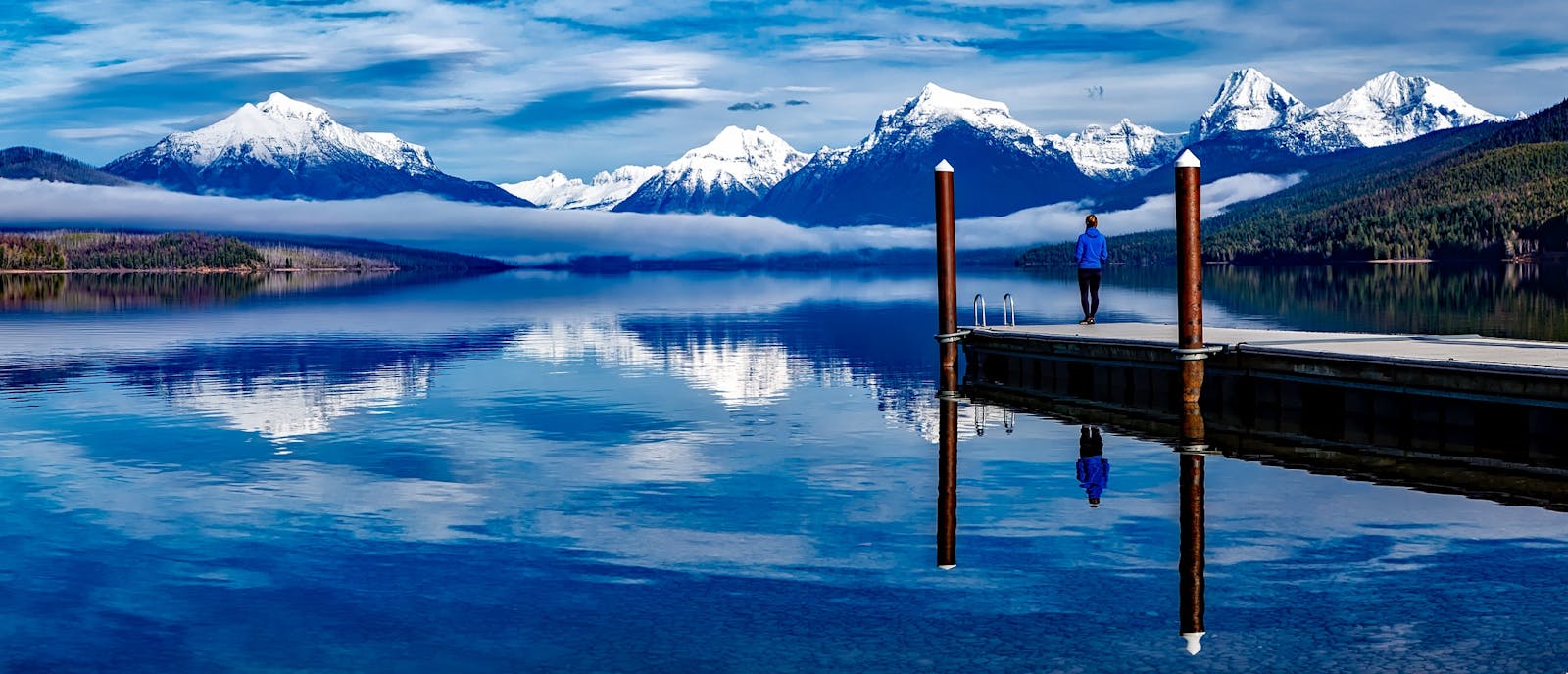 A serene lake with snowcapped mountains reflecting in the water, enhancing the tranquil outdoor setting.