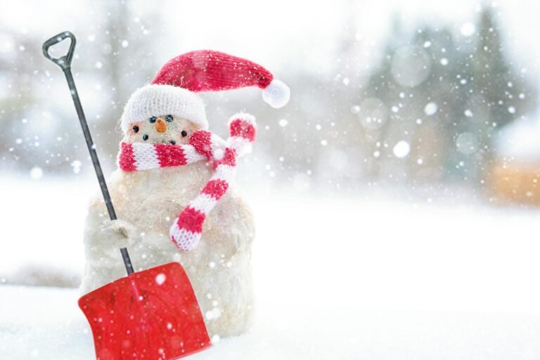 Charming snowman wearing a Santa hat and scarf with a red shovel in a snowy setting.