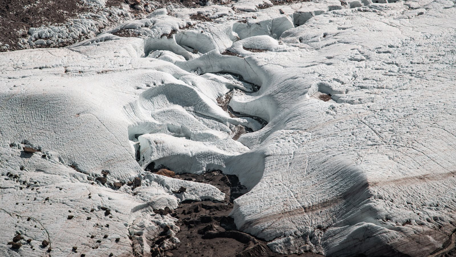 Aerial photograph showcasing the intricate patterns of a snowy glacier in a rugged outdoor environment.